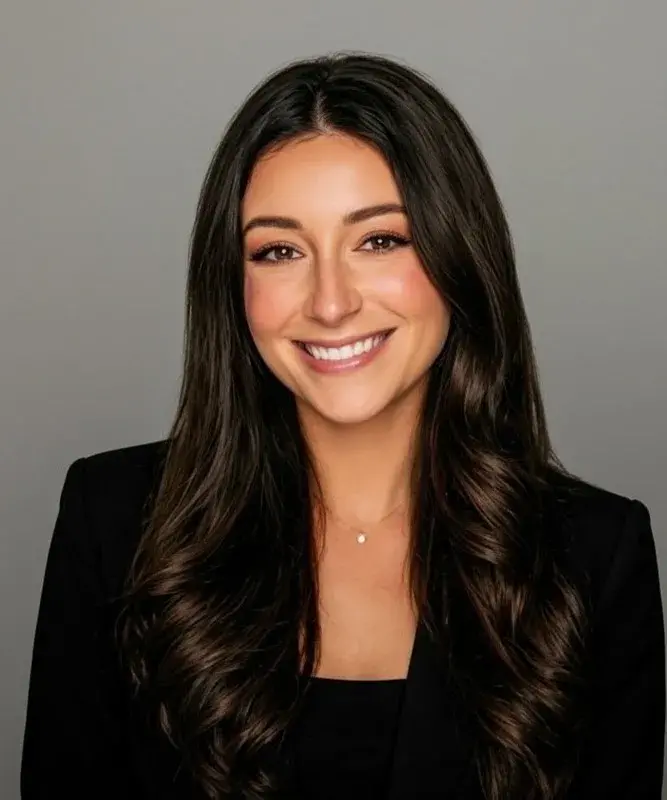 Smiling woman in black blazer against gray background