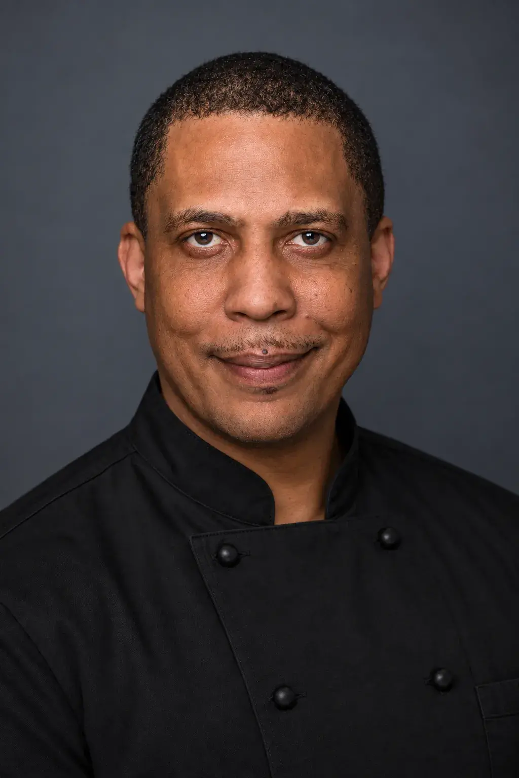 Portrait of a smiling chef in a black uniform