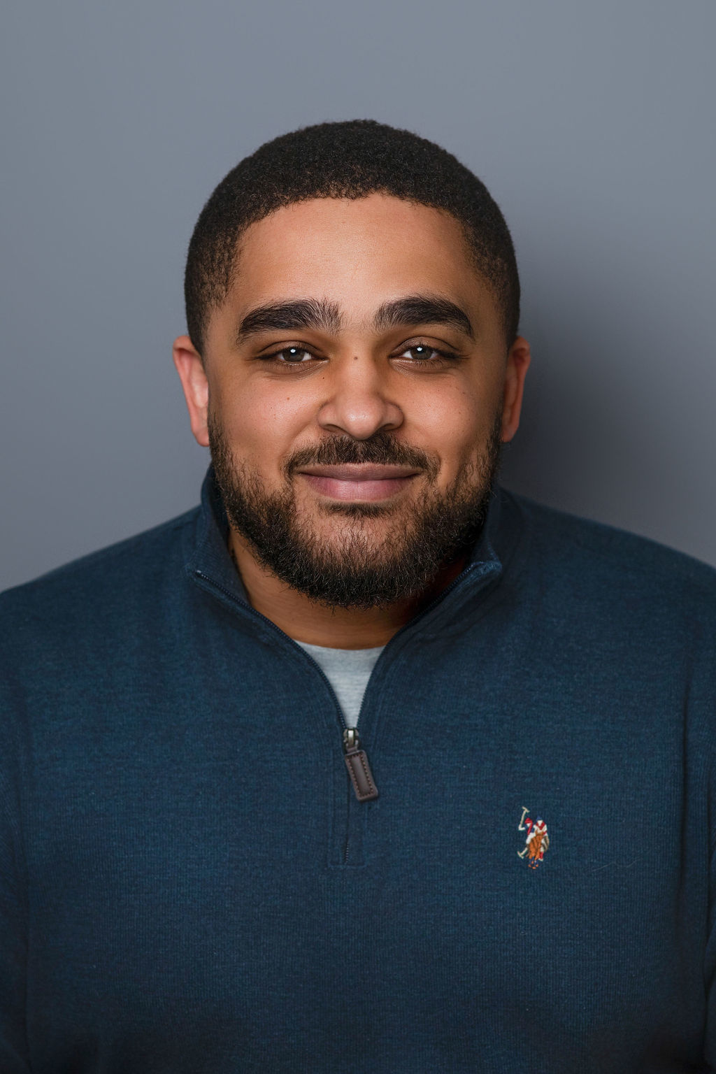 Smiling man in blue quarter-zip sweater portrait