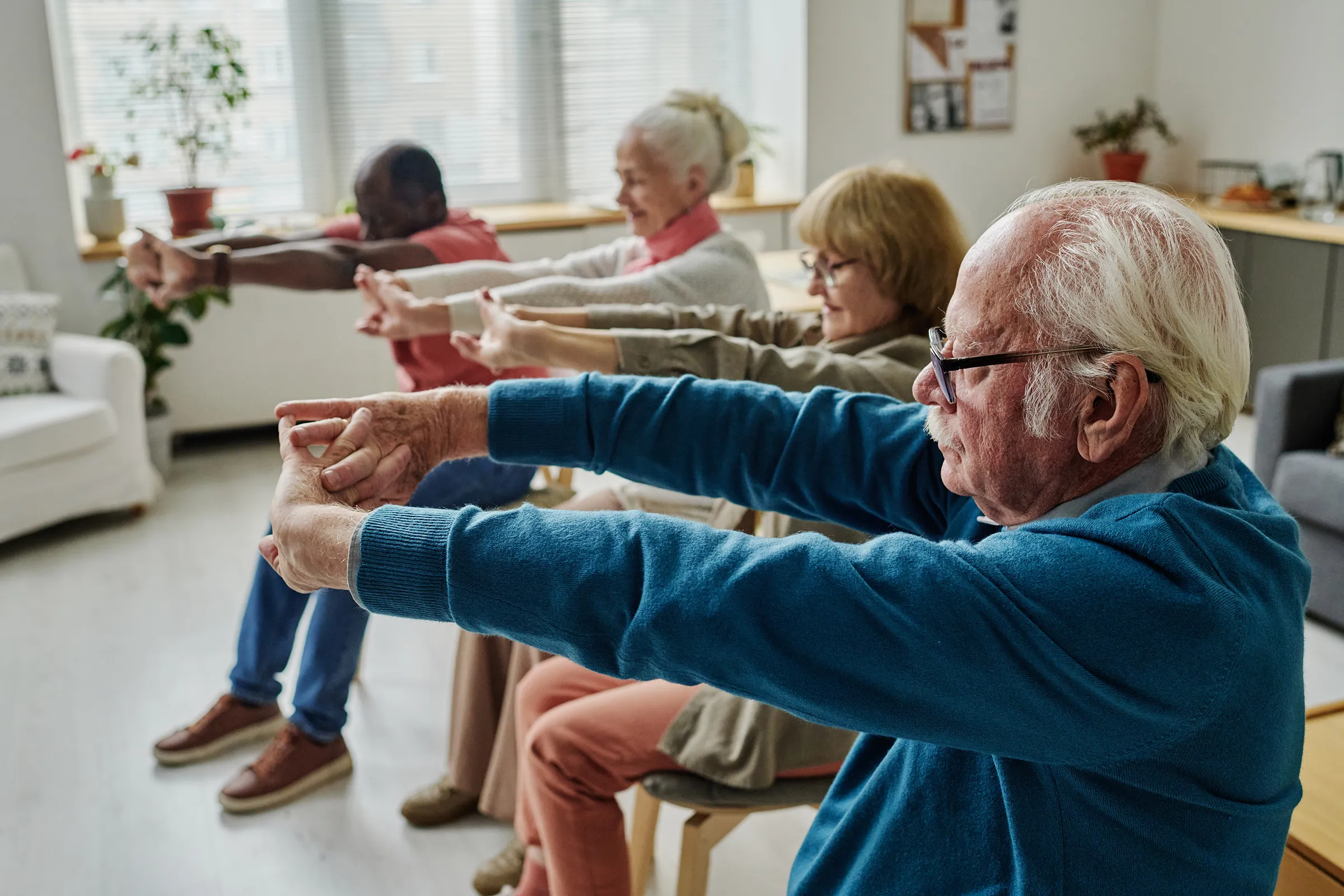 Seniors stretching arms during seated exercise class